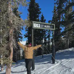 Alex standing in front of a trail sign showing the name of the train is Alex at Arapahoe Basin