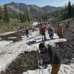 The snow ran out and people are taking of their equipment to hike to the bottom.